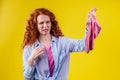 Curly ginger redhead woman in a cotton shirt gesture smells bad holding a dirty pink sock out a disgusted look on her Royalty Free Stock Photo