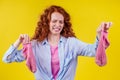 Curly ginger redhead woman in a cotton shirt gesture smells bad holding a dirty pink sock out a disgusted look on her Royalty Free Stock Photo