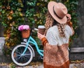 Curly girl against bike parked to wall covered with ivy. Royalty Free Stock Photo