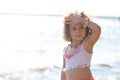 Curly girl pink dress with shell decorations on the beach