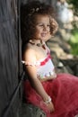 Curly girl in a pink dress with shell decorations on the nature