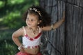 Curly girl in a pink dress with shell decorations on the nature