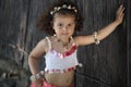 Curly girl in a pink dress with shell decorations on the nature