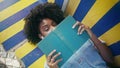 Curly girl posing book lying on campus bench close up. Student reading textbook Royalty Free Stock Photo