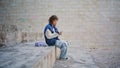 Curly girl reading cellphone message on street. Teenager browsing smartphone Royalty Free Stock Photo