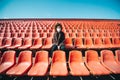 Curly girl in a surgical mask sitting in an empty stadium during epidemic disease Covid-19