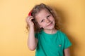 Curly girl takes off or puts on a red bow from her hair, looks smiling at the camera.