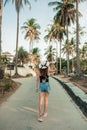 Happy woman hips in jeans shorts and hat walking at the hotel near palm trees background Royalty Free Stock Photo