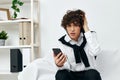 curly guy in the room on the couch with the phone online learning living room Royalty Free Stock Photo
