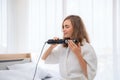 Curly Hair. Beautiful Smiling Woman With Long Blonde Wavy Hair Ironing It, Using Curling Iron. Happy Girl With Gorgeous Healthy