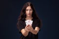 Curly hair brunette is posing with playing cards in her hands. Poker concept on a black background. Casino. Royalty Free Stock Photo
