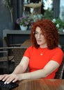 Curly hair business woman in red clothes works with laptop ooutdoors. Royalty Free Stock Photo