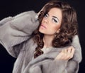 Curly hair. Makeup. Beautiful girl portrait. Brunette fashion woman in mink fur coat with sensual lips posing isolated on black b Royalty Free Stock Photo