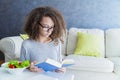 Curly hair teen girl reading book and eating salad Royalty Free Stock Photo