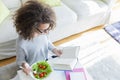 Curly hair teen girl reading book and eating salad Royalty Free Stock Photo