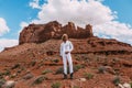 A curly haired blonde man posing around the famous Buttes of Monument Valley from Arizona, USA, wearing white linen shirt and Royalty Free Stock Photo