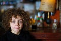 Curly haired boy making faces at a bar