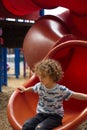 Curly haired boy sitting on slide