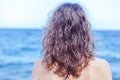 Curly haired brown-haired girl standing on the beach with her ba Royalty Free Stock Photo