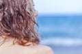 Curly haired brown-haired girl standing on the beach with her ba Royalty Free Stock Photo