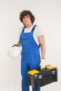 Curly haired builder lifting up toolbox and white helmet in studio.