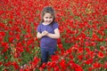 Curly-haired little girl in red flowers field Royalty Free Stock Photo