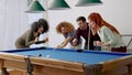 Curly-haired man misses crucial shot in pool game, others cheer.