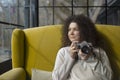 Curly haired photographer woman holding her camera in a cafe and shooting Royalty Free Stock Photo