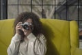 Curly haired photographer woman holding her camera in a cafe and shooting Royalty Free Stock Photo