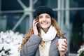 Curly haired woman using her smartphone and holding paper cup with coffee. Young girl talking on her mobile phone while Royalty Free Stock Photo