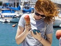 Curly haired young woman with ice cream and smart phone by the seaside Royalty Free Stock Photo