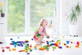 Curly laughing toddler girl playing with colorful blocks