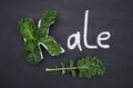 Curly-leaf kale cabbage inside letter K shaped plate, chalk inscription KALE on blackboard. Healthy food concept. Flat lay or top