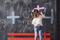 Curly little baby girl drawing with crayon color on the wall. Works of child. Cute pupil writing on chalkboard Royalty Free Stock Photo