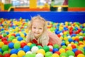 Curly little girl having fun in ball pit with colorful balls