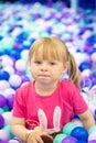 Curly little girl having fun in ball pit with colorful balls. Child playing on indoor playground. Kid jumping in ball Royalty Free Stock Photo