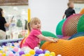 Curly little girl having fun in ball pit with colorful balls. Child playing on indoor playground. Kid jumping in ball Royalty Free Stock Photo