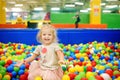 Curly little girl having fun in ball pit with colorful balls Royalty Free Stock Photo