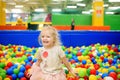 Curly little girl having fun in ball pit with colorful balls Royalty Free Stock Photo