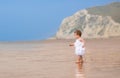 Curly little girl in a white dress on exotic beach Royalty Free Stock Photo