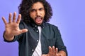 Curly male got everything under control, raising hand up in calm down, wait sec or stop gesture Royalty Free Stock Photo