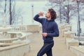 Curly Male runner drinks water from a bottle in park on the stai