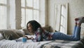 Curly mixed race student girl lauging using laptop for sharing social media lying in bed at home Royalty Free Stock Photo