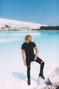 Curly model with curly hair is posing. Dressed all black. Tropical view, awesome nature. Crystal clear water, blue sky. Summer