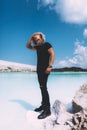 Curly model with curly hair is posing. Dressed all black. Tropical view, awesome nature. Crystal clear water, blue sky. Summer