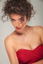 Curly model in red dress posing while leaning on side Royalty Free Stock Photo