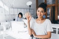 Curly mulatto female student posing with smile and okay sign after difficult test in international university. Indoor Royalty Free Stock Photo