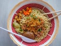 Curly noodles with minced meat, red chili slices, pickles, fried onions and egg topped in a patterned white bowl Royalty Free Stock Photo