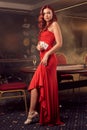 Charnimg sexy woman is posing against a poker table in luxury casino.