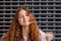 Curly redheaded girl looks at the camera with a funny expression on her face, pulling up her chin a little bit.